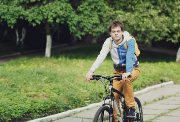 cute guy riding in the park on a bicycle