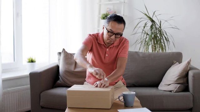 man opening parcel box with paper knife at home