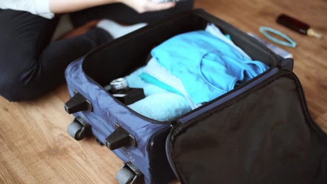 hands packing travel bag with personal stuff