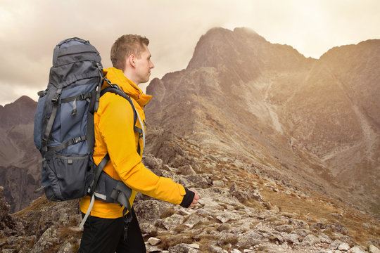 hiker man with big backpack walking in sunset mountains