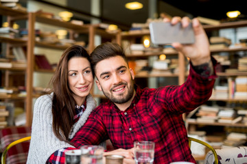 Couple at cafe bar, taking a photo.