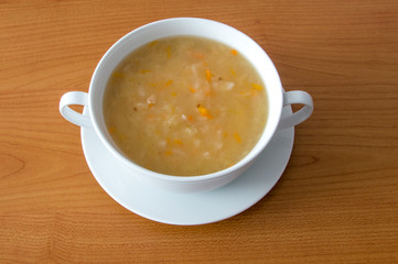 Polish cabbage soup in a white bowl on wooden background. Soup knows in Poland as Kapusniak.