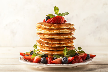 Homemade pancakes with berries and fruit on a white background.