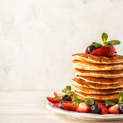 Homemade pancakes with berries and fruit on a white background.