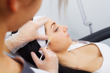 Hands of cosmetologist making injection in face, lips. Young woman gets beauty facial injections in salon. Face aging, rejuvenation and hydration procedures. Aesthetic cosmetology. Close up.