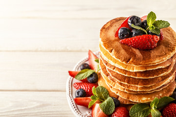 Homemade pancakes with berries and fruit on a white background.