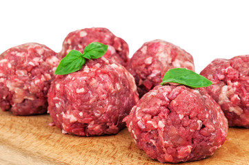 raw meatballs with basil leaves