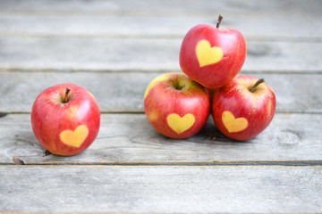 Red apple with shape of heart on a gray wooden  background , cardiology, holiday  and health concept