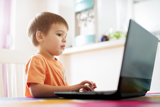 Little cute boy playing games on laptop.