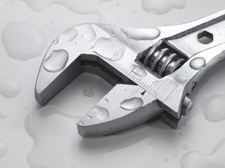 adjustable wrench on wet background with water drops, macro