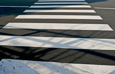 Crosswalk with shadowson on the newly paved road. 