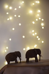 2 Holzelefanten vor gelbem Hintergrund mit Lichtpunkten