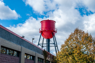 Industrial building with water reserve on roof. red water tower on top of office building. Isolated water tower structure. Architecture detail with water tower. Abstract architectural design and art. 