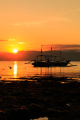 Sunset over a tropical asian island with a local boat in the foreground