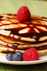 Pile of Pancakes with blueberries and raspberries and chocolate sauce