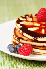 Pile of Pancakes with blueberries and raspberries and chocolate sauce