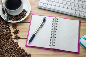 Office desk table with pen, keyboard on notebook, cup of coffee and flower. Top view with copy space .