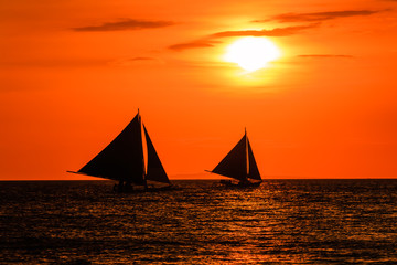 Fototapeta na wymiar Sailing boats at sunset on a tropical ocean