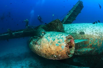 Fotobehang SCUBA divers explore the wreckage of a sunken airplane © whitcomberd