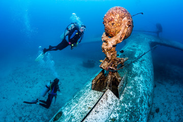 SCUBA divers explore the undercarriage of an underwater plane wreck