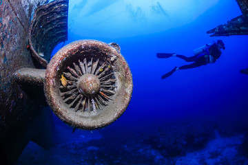 SCUBA divers near the corroded jet engine of an underwater plane wreck
