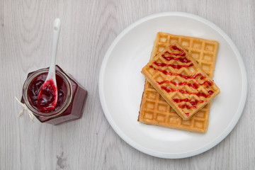 Waffles with berry jam, on a white plate with a spoon