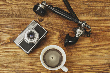 Cup of coffee,camera and a notebook on wooden table as business concept.