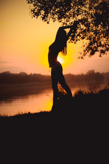 Silhouette of dancing girl at sunset by the lake