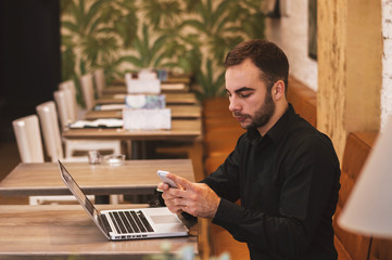 Business man with the laptop and phone sits at a table in cafe