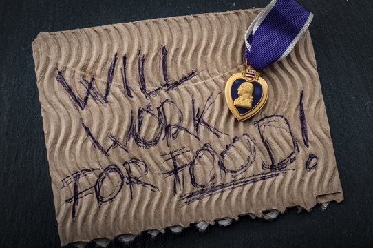 Veterans reintegration and social issues concept with cardboard sign reading “will work for food” and a purple heart medal illustrating the reality of many veterans that struggle to join civilian life