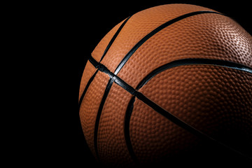 Sports, athletics and basketball concept with hard spotlight on orange ball against a dark background with copy space