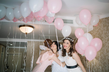 beautiful and young bride in veil with bridesmaids having fun