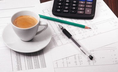Calculator, papers, pen,  pencil and cup of coffee on the table