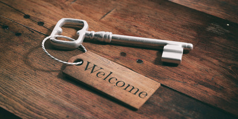 Old key with tag welcome on a wooden background. 3d illustration