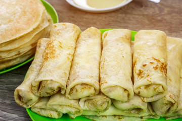 Twisted delicious pancakes on wooden table, snack