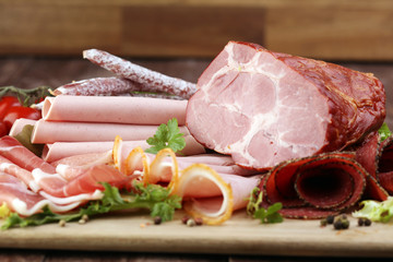 Food tray with delicious salami, pieces of sliced ham, sausage, tomatoes, salad and vegetable - Meat platter with selection