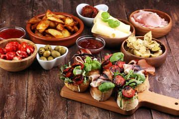 Italian antipasti wine snacks set. Cheese variety, Mediterranean olives, pickles, Prosciutto di Parma, tomatoes, artichokes and wine in glasses