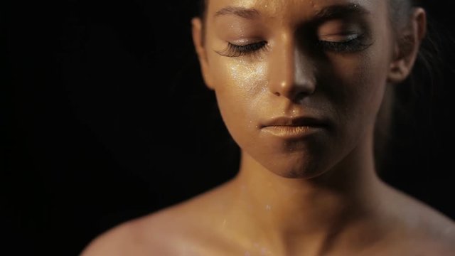 Professional model posing with bronze art makeup on her face closeup