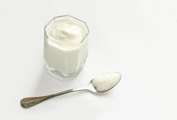 glass with natural yoghurt and spoon on white table