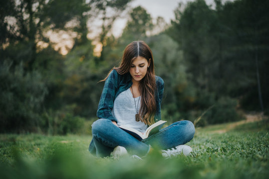 Chica leyendo un libro en el bosque