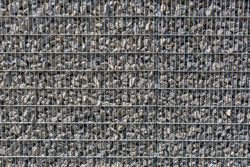 Hintergrund, aufgeschüttete graue Steine hinter einem Gitter