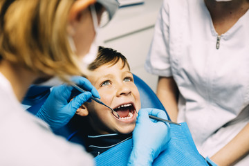 Dentists with a patient during a dental intervention to boy.