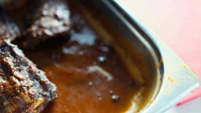 Closeup of chef take hot meat dishes with pork ribs with gravy sauce at restaurant kitchen