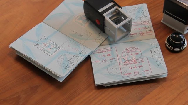 Passports and Stamps on Brown Wooden Desk.