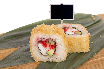 Sushi rolls on wooden Board with leaves of leeks and black sign for logo and name