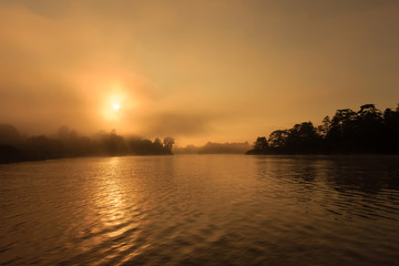Fototapeta na wymiar Misty sunrise over a jungle river