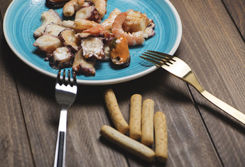 Seafood salad next to bread sticks on wooden table. Horizontal shoot.