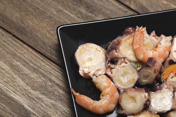Tasty seafood salad on black plate. Horizontal shoot.