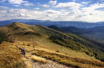 Group of people walking on the peak in mountains during late afternoon