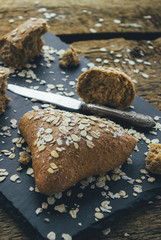 Homemade bread triangular shape of oatmeal sprinkled with oatmeal and vintage knife. Concept  healthy eating.